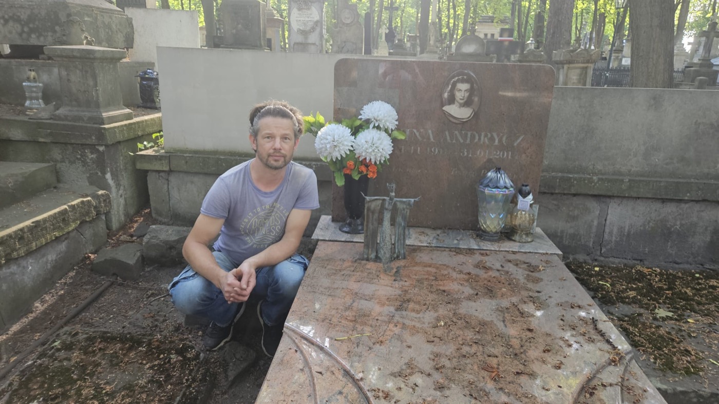 Dariusz Zieliński przy rzeźbie swojego autorstwa na grobie Niny Andrycz
